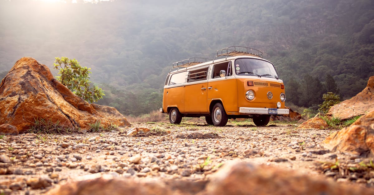 Classic VW van parked on rocky terrain with mountains in Alegría, El Salvador.
